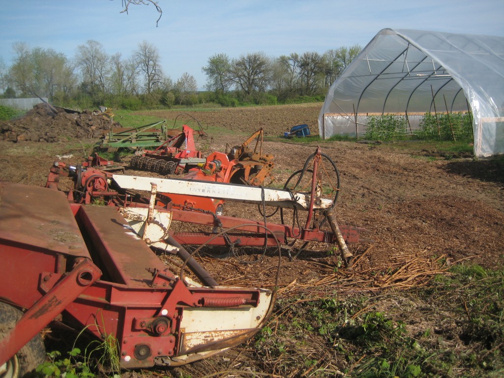 Tractor implements moved and all lined up in a tidy row — a few there to prepare for selling. Note the newly worked up field in the background!