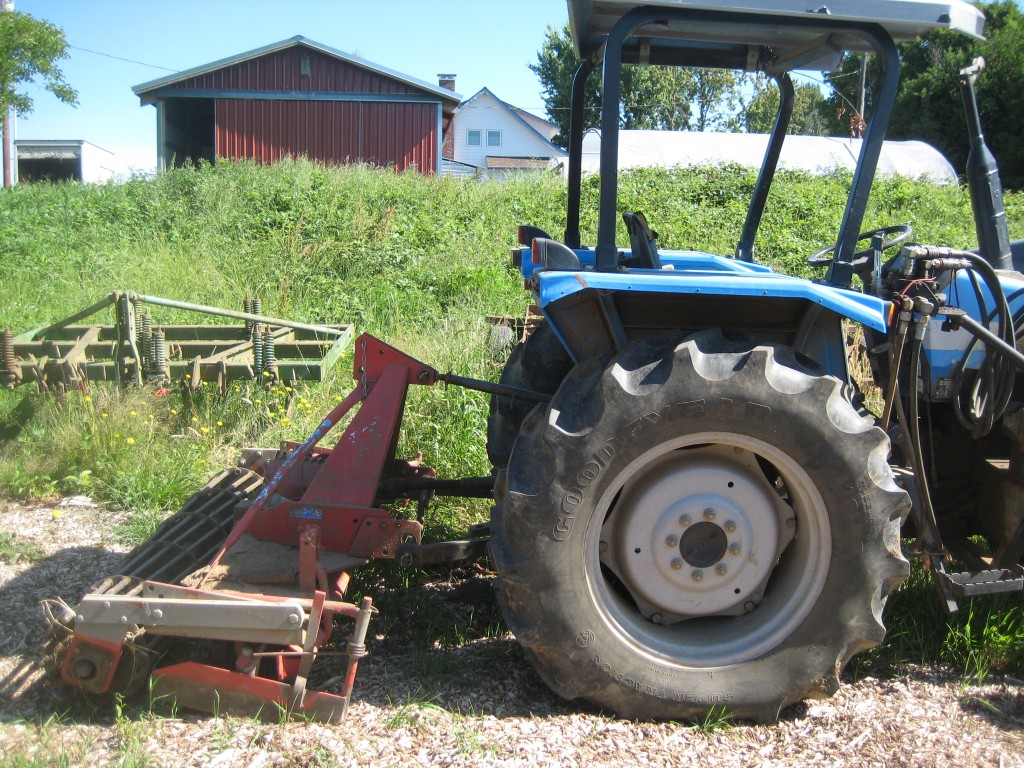 After the chisel plow comes the power harrow, which has lots and lots of vertical tines that spin around in the soil (again without turning it over). This is the final tillage that Casey uses on a bed before planting it. And of course, there's our good old tractor. Just the right size for us. (Not too big; not too small.)